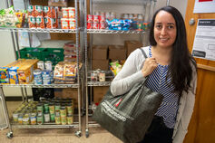 IU student holding shopping bag in front of shelves stocked with food and canned goods.